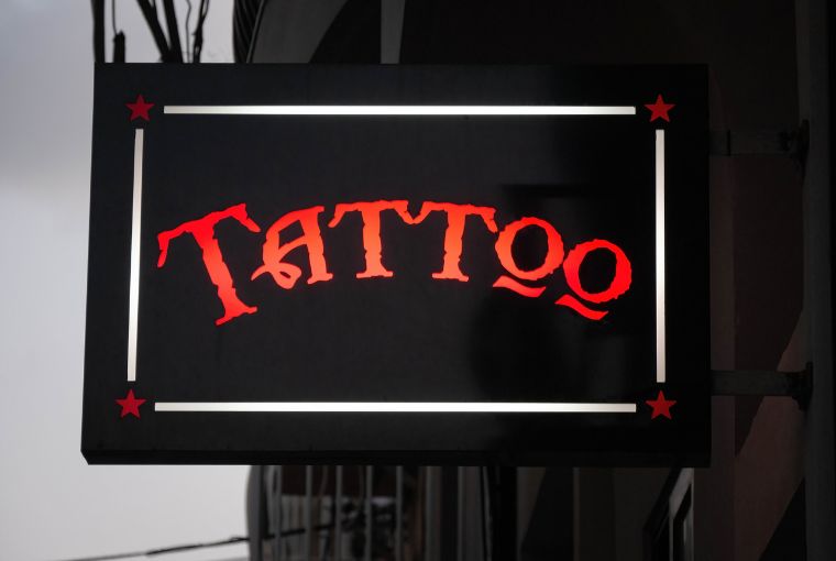 A bright red sign with the word "Tattoo" glows outside a tattoo studio.