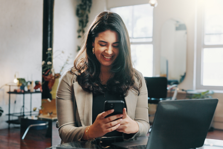 A salon owner uses salon management software on her mobile phone