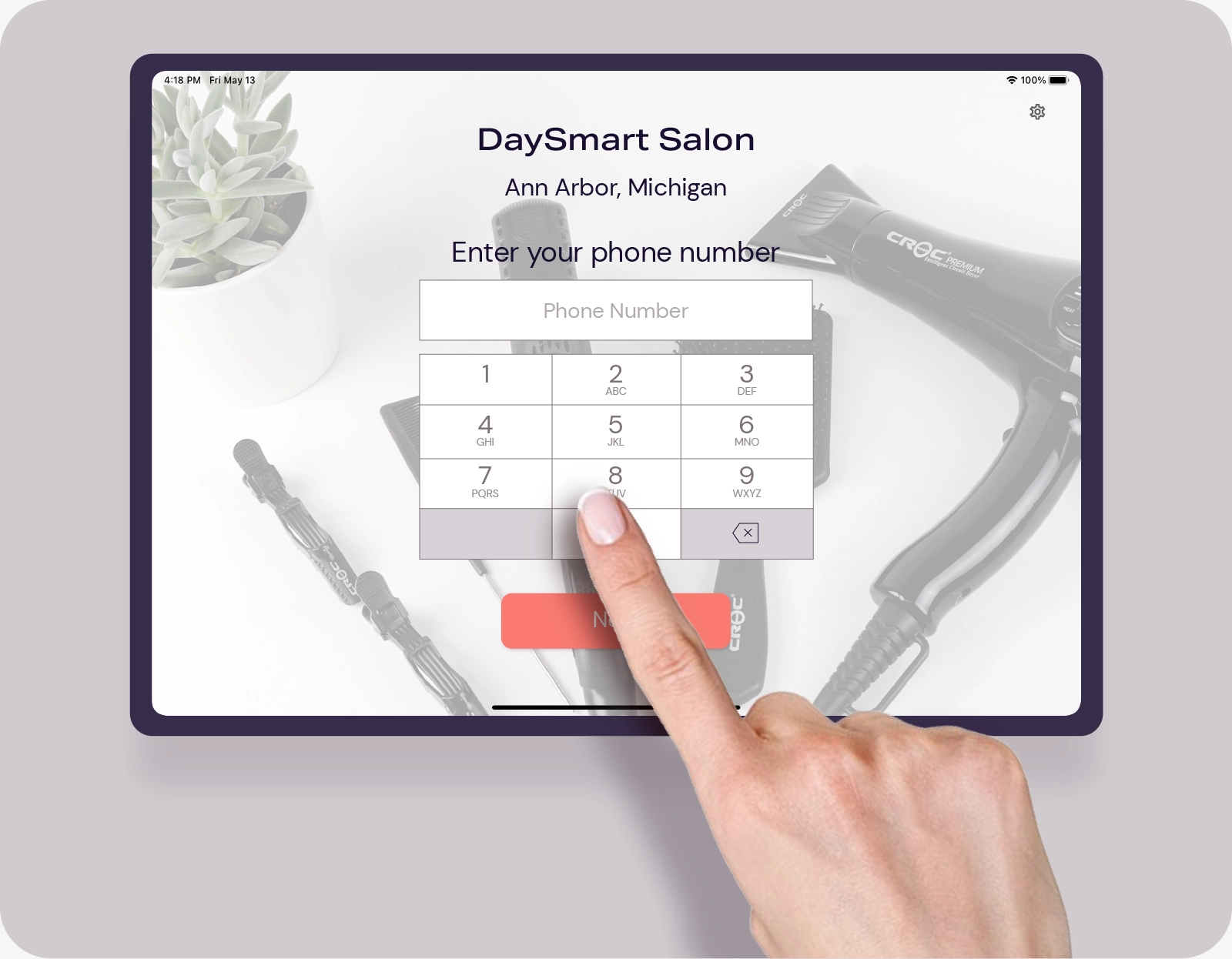 Hand entering phone number on a digital salon check-in screen for DaySmart Salon.